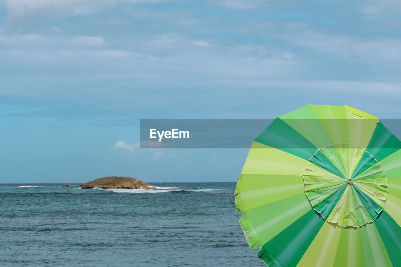 water, sky, sea, cloud, nature, umbrella, protection, land, day, beauty in nature, beach, scenics - nature, horizon over water, wind, outdoors, blue, no people, horizon, security, tranquility, ocean, sailing, tranquil scene, environment, windsports, green, parasol, multi colored