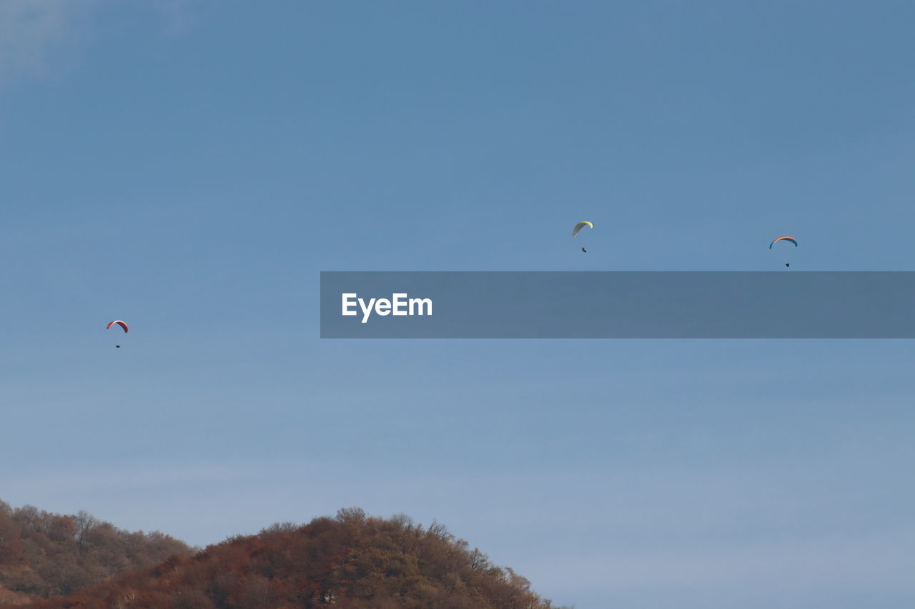 LOW ANGLE VIEW OF FLYING KITE AGAINST CLEAR BLUE SKY