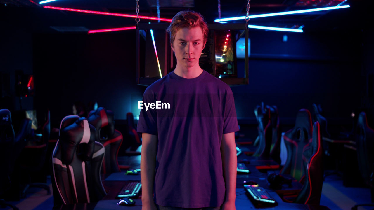 Portrait of young man standing in internet cafe