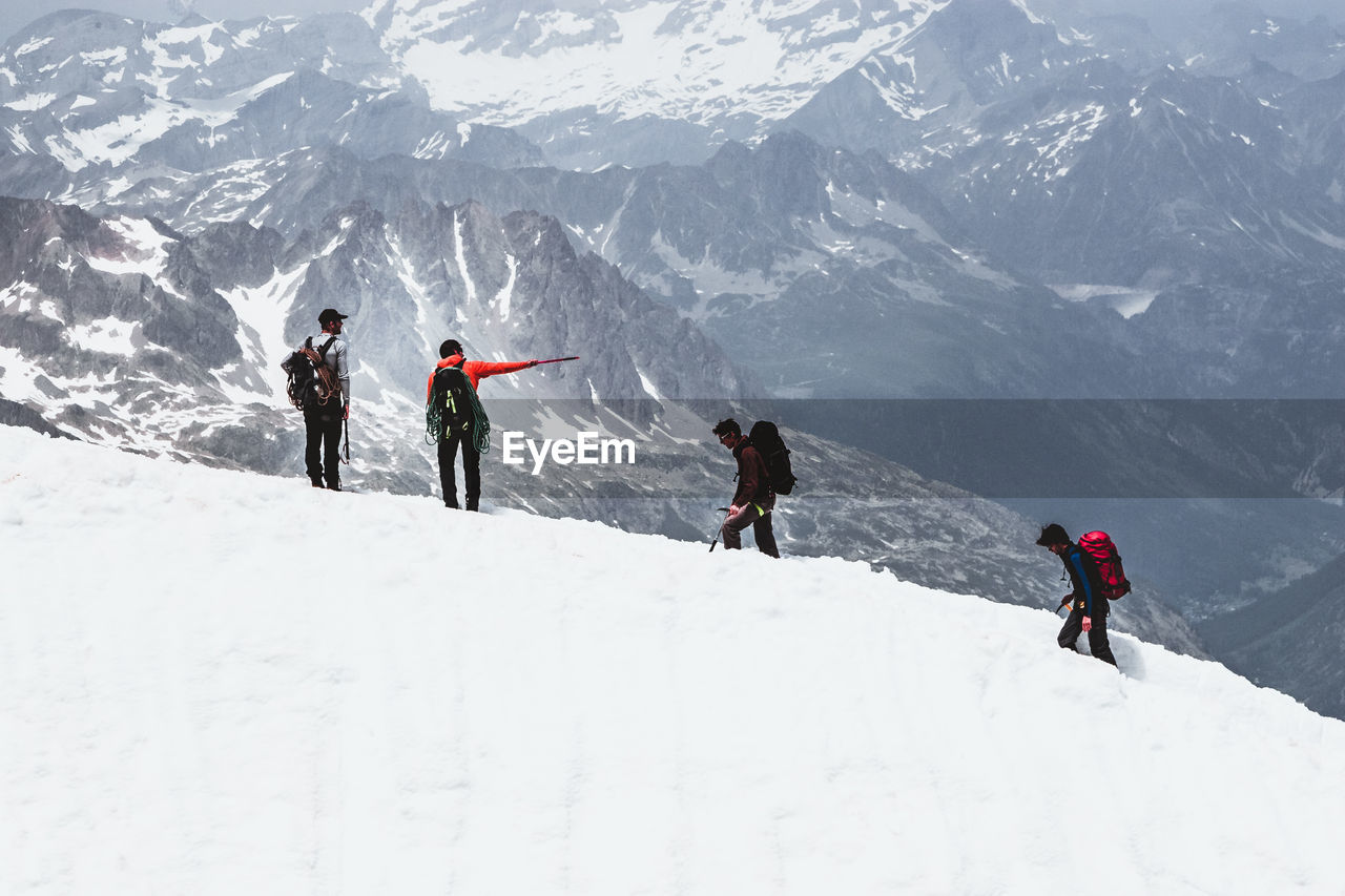 PEOPLE WALKING ON SNOWCAPPED MOUNTAINS