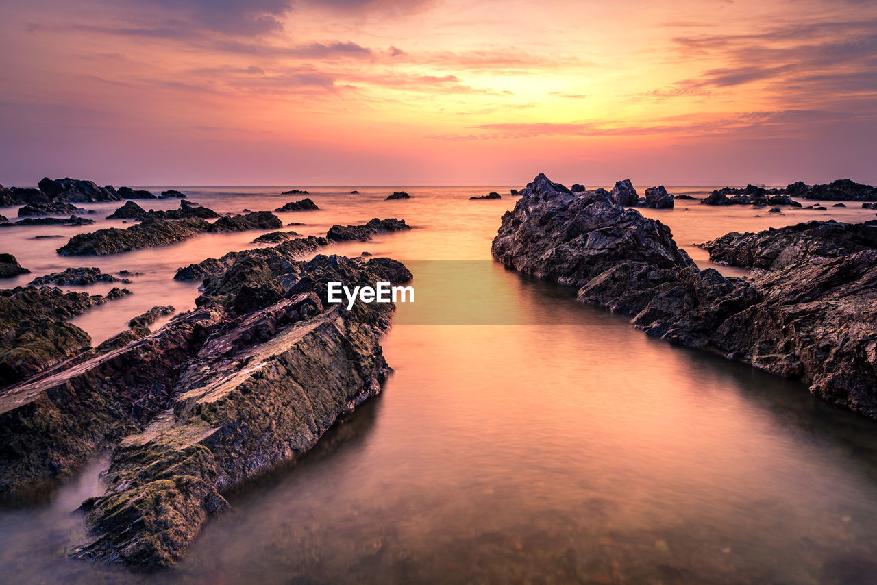 ROCK FORMATION IN SEA AGAINST ROMANTIC SKY