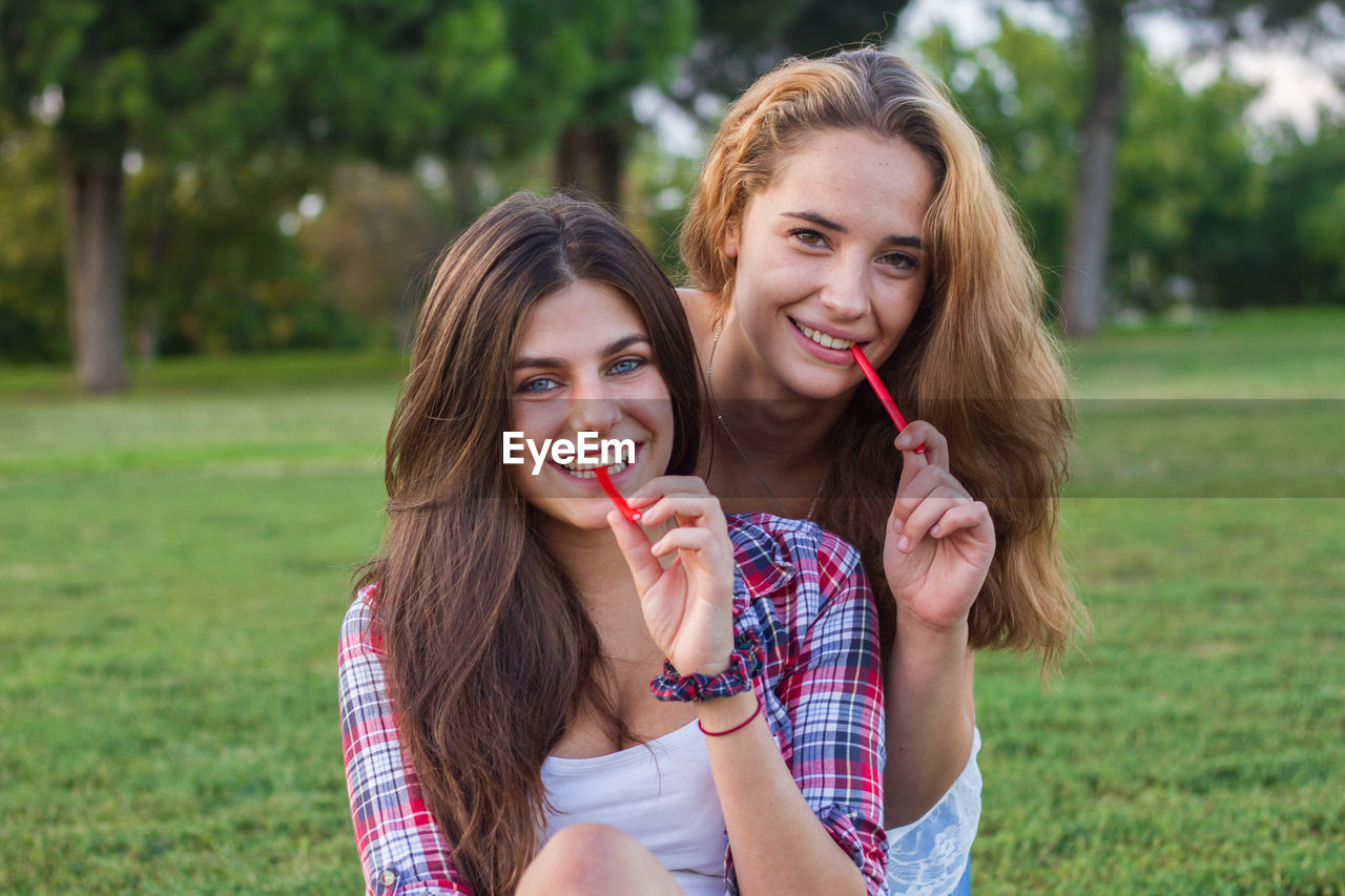 Portrait of young women eating candies on field