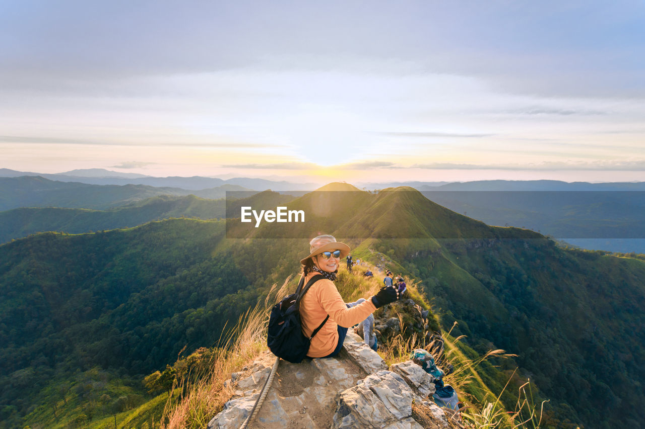 Woman sitting on mountain against sky