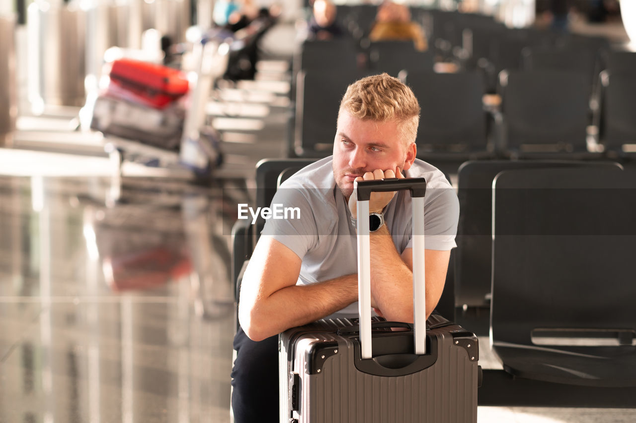 Man waiting in airport with baggage 