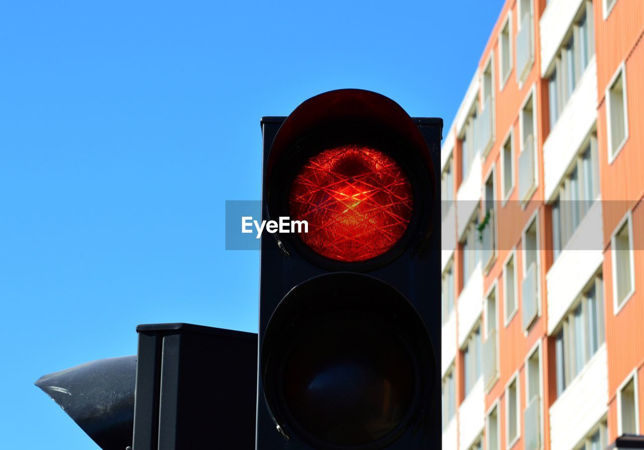 Low angle view of road sign against clear blue sky