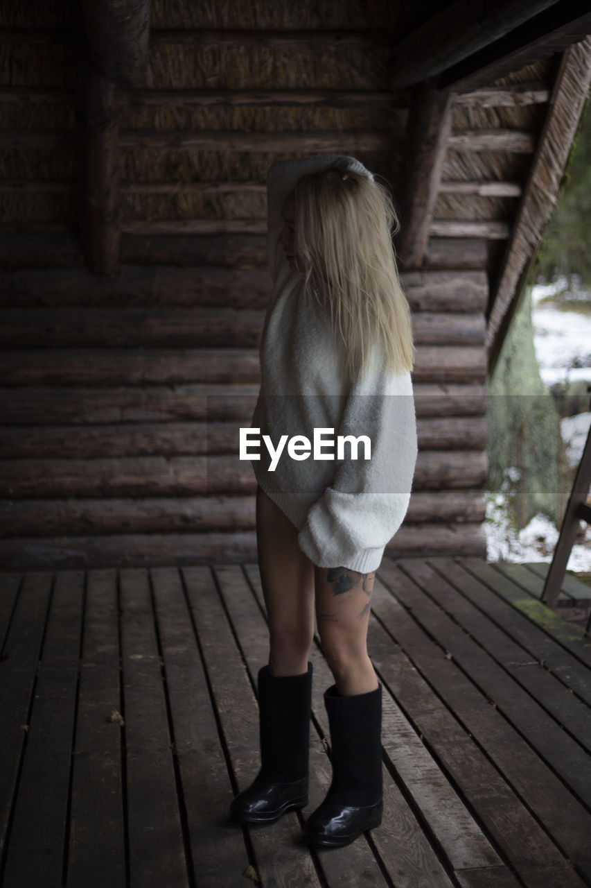 one person, wood, women, adult, full length, architecture, footwear, clothing, blond hair, rear view, standing, young adult, day, built structure, lifestyles, leisure activity, fashion, dress, hairstyle, female, nature, outdoors, shoe, black, photo shoot, casual clothing