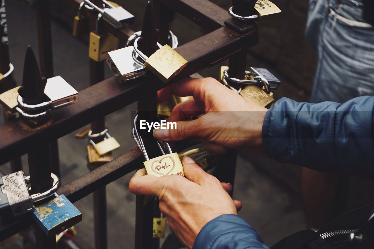 Cropped image of man putting padlock on railing