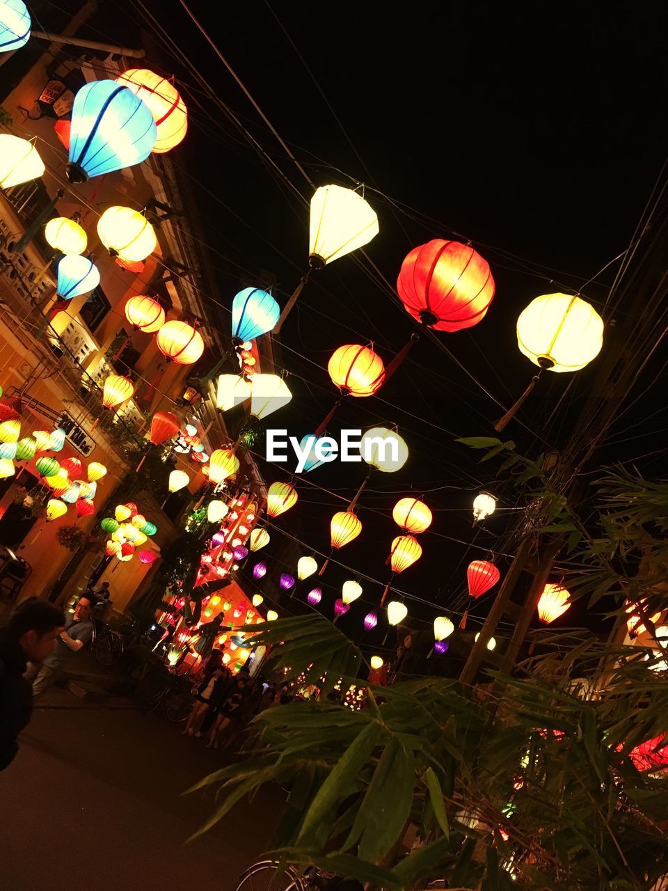 LOW ANGLE VIEW OF ILLUMINATED LANTERNS HANGING ON WALL