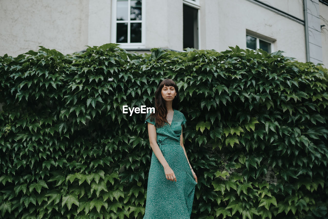 Portrait of woman standing against plants