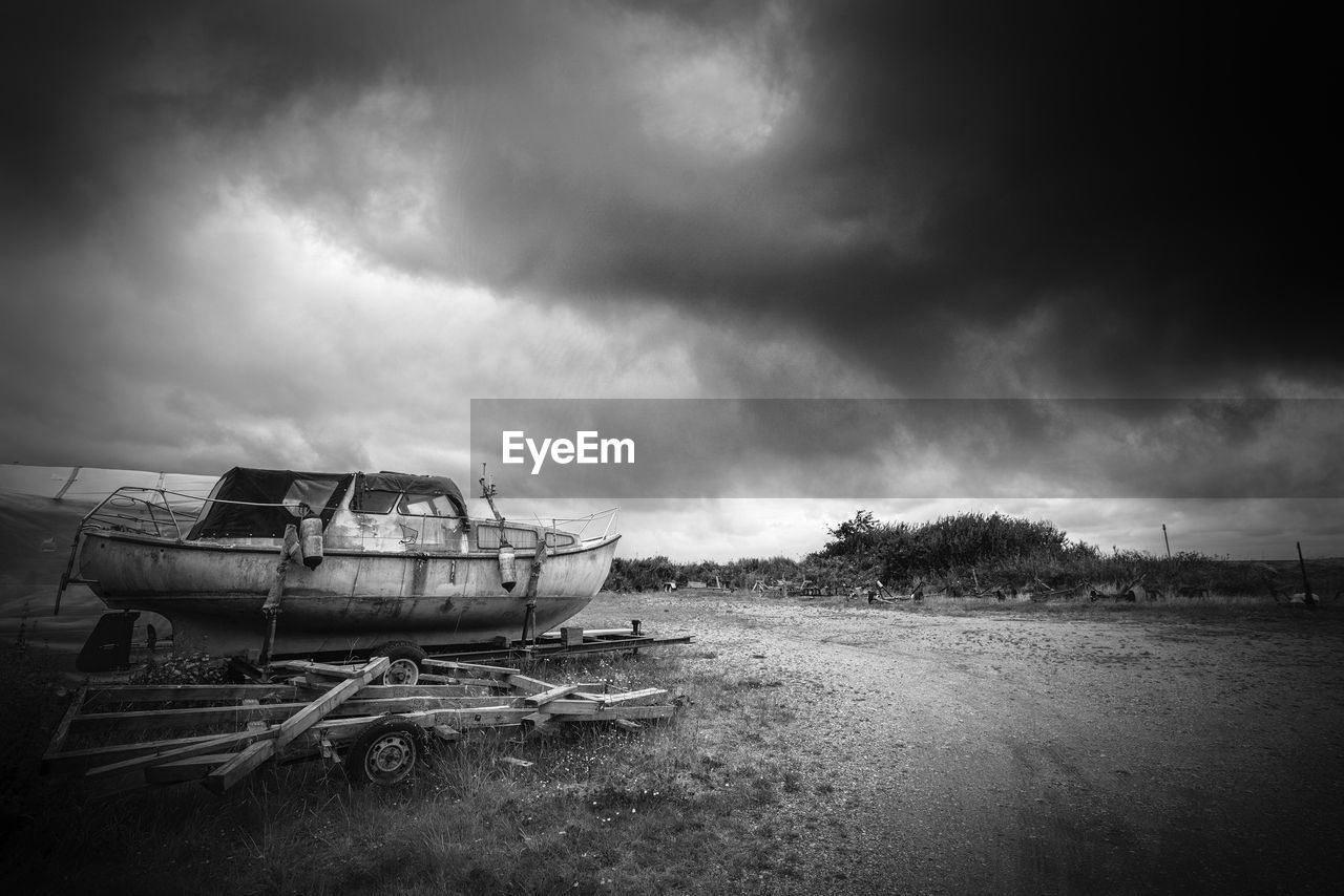 ABANDONED BOAT ON FIELD AGAINST SKY