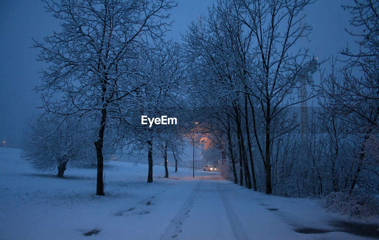 SNOW COVERED ROAD PASSING THROUGH LANDSCAPE