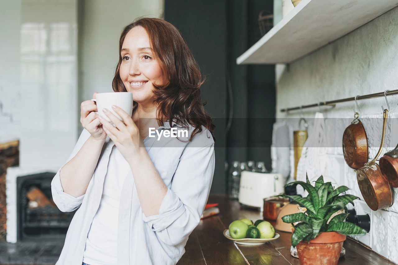 Woman holding coffee cup at home