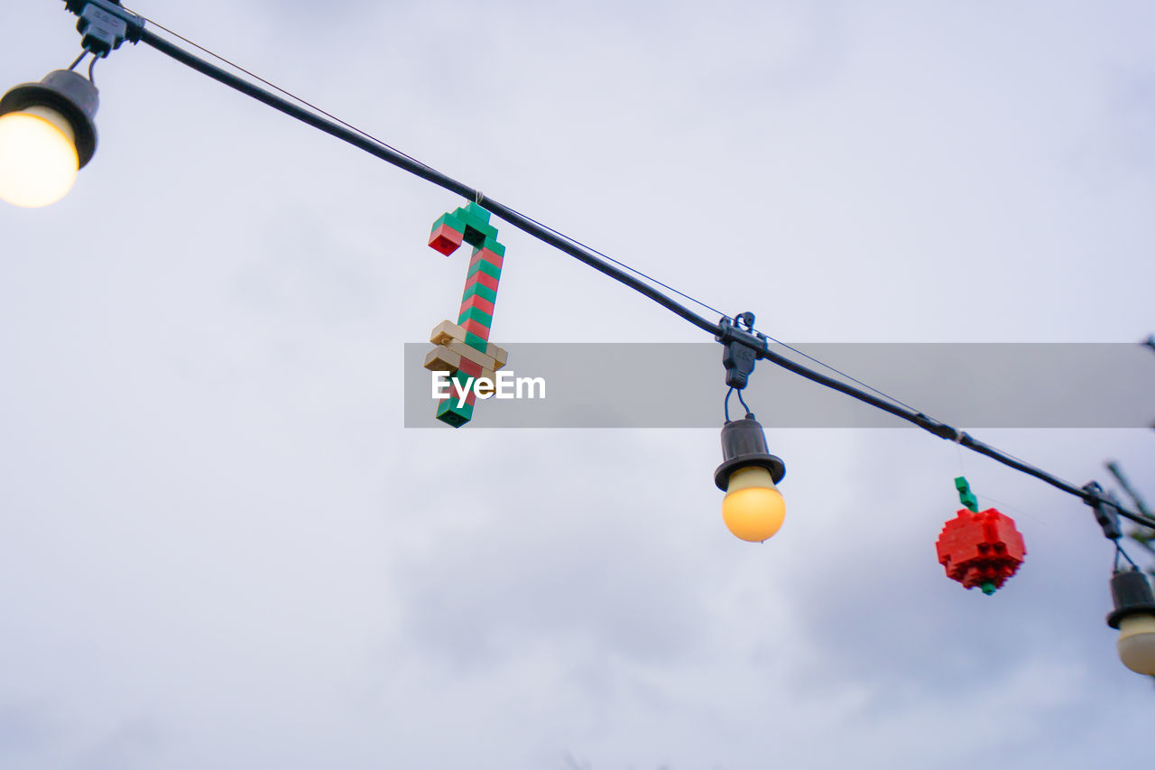 LOW ANGLE VIEW OF MULTI COLORED LIGHT BULBS HANGING AGAINST SKY