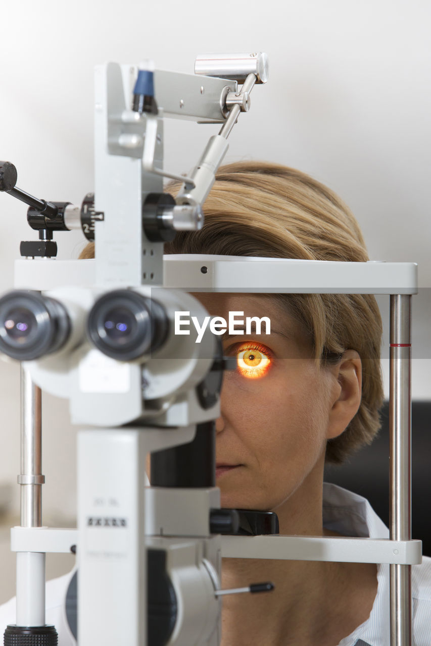 Mature woman looking through eye test equipment