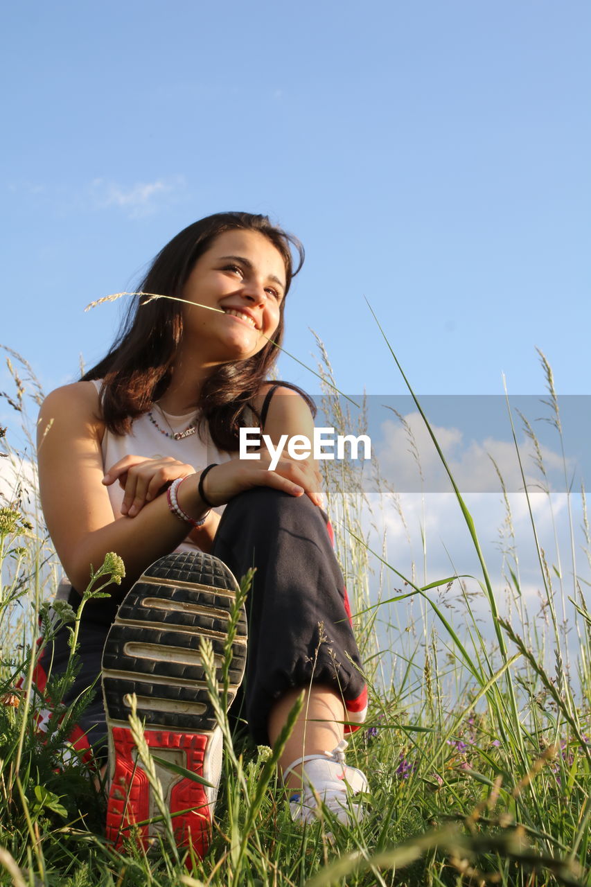 Young woman smiling on field against sky