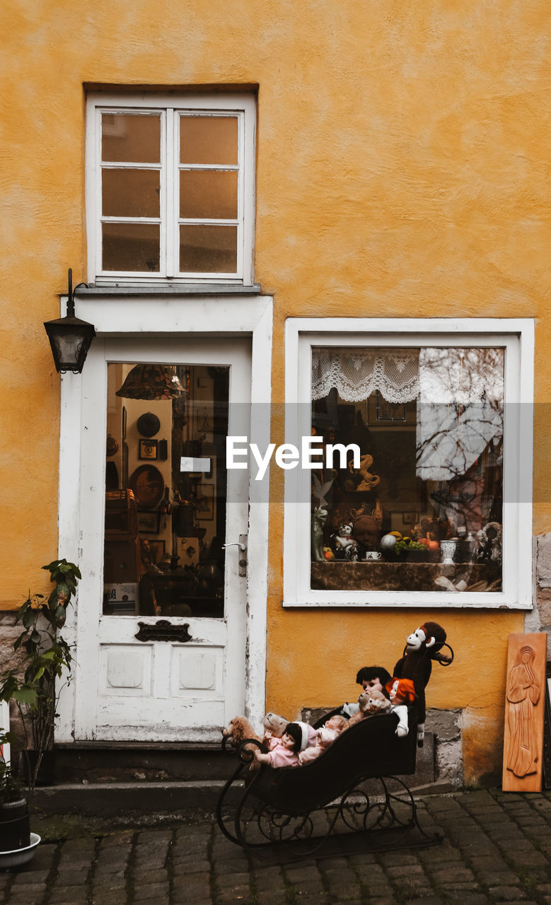 MAN PHOTOGRAPHING WOMAN SITTING ON WINDOW OF A HOUSE