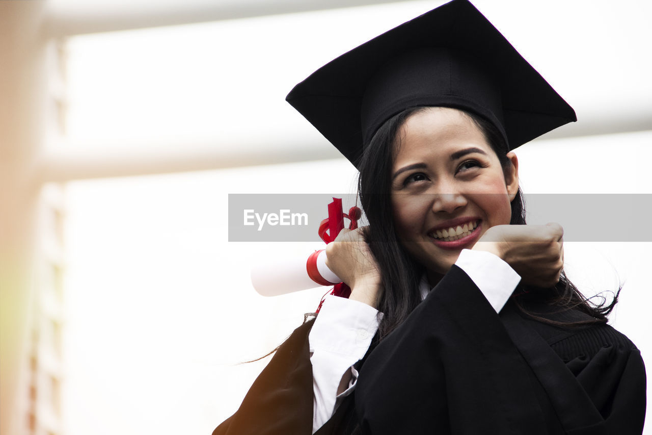 Cheerful young woman in graduation gown