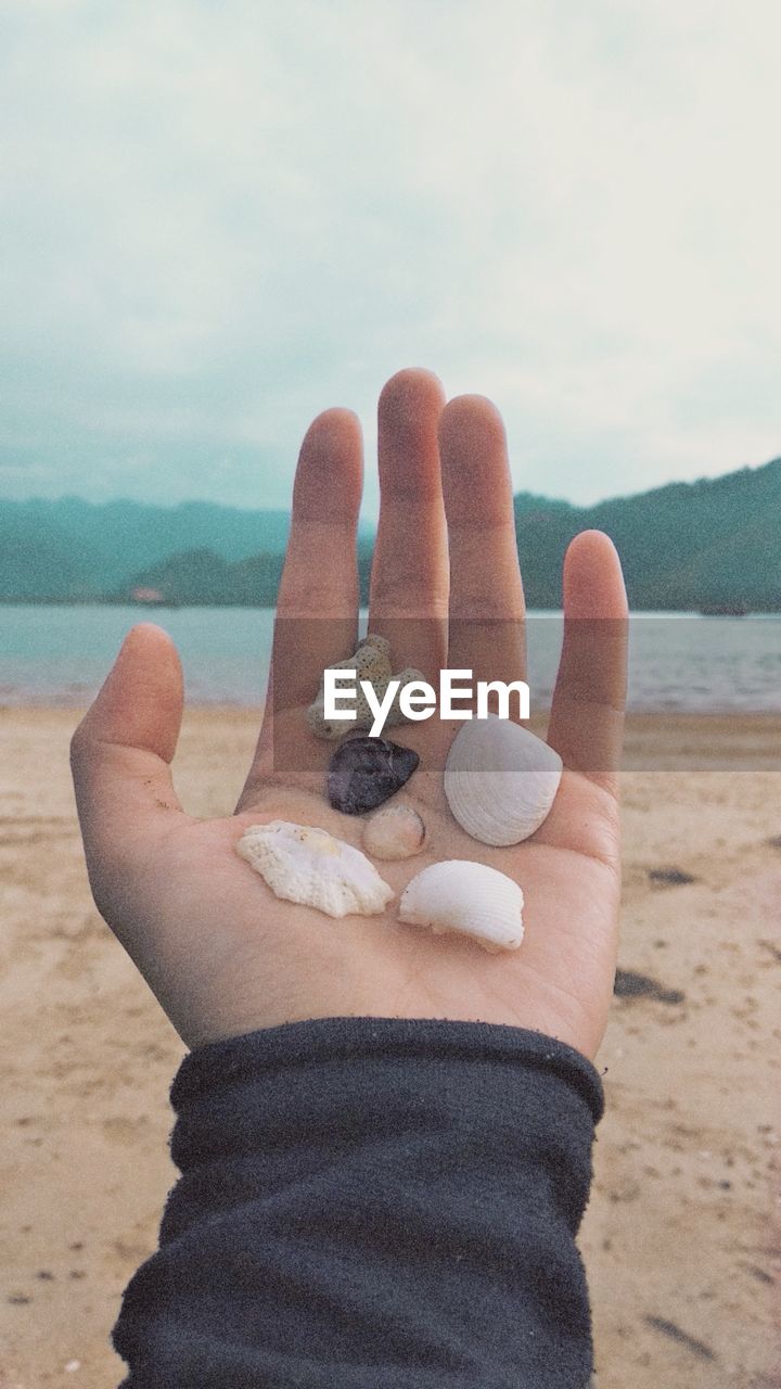 LOW SECTION OF PERSON HOLDING HANDS ON BEACH