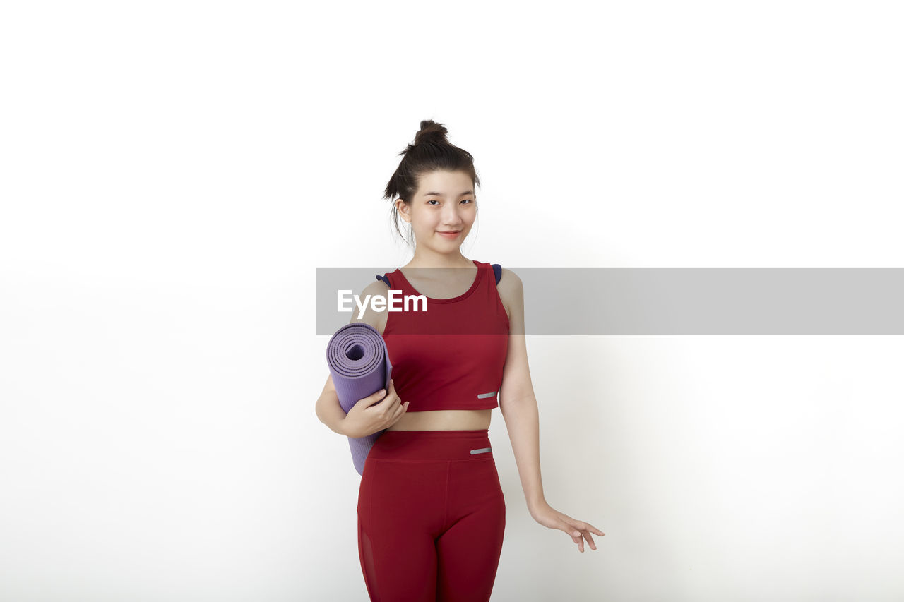 PORTRAIT OF A SMILING YOUNG WOMAN AGAINST WHITE BACKGROUND