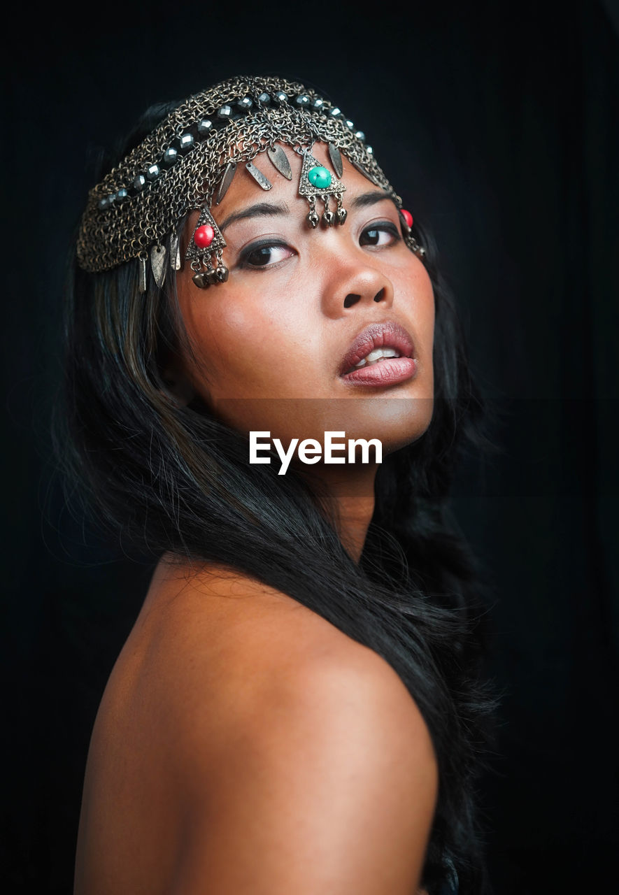 close-up portrait of young woman with eyes closed against black background