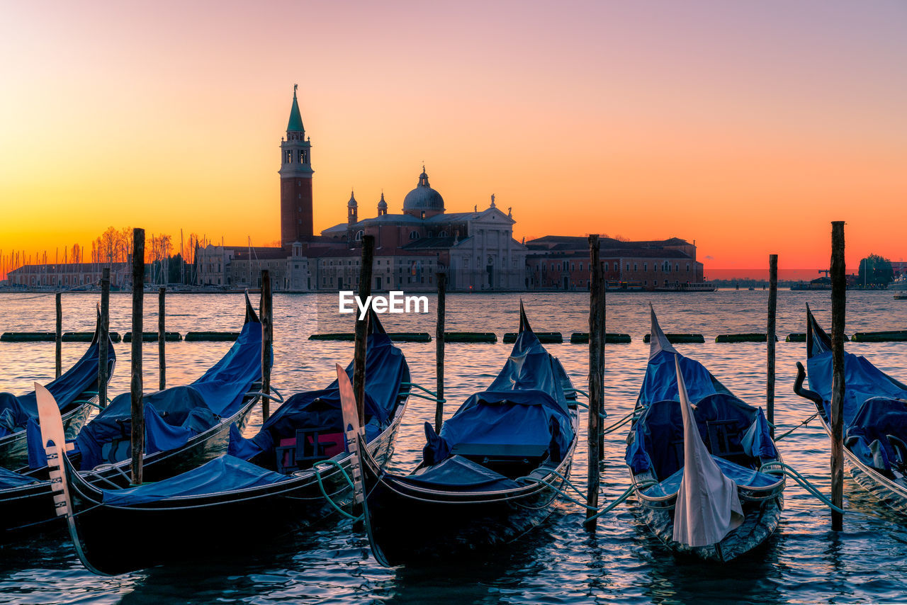 Gondolas moored in canal at sunset