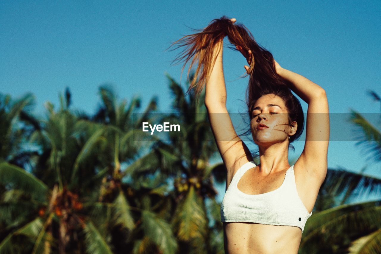 Portrait of young woman standing against clear sky