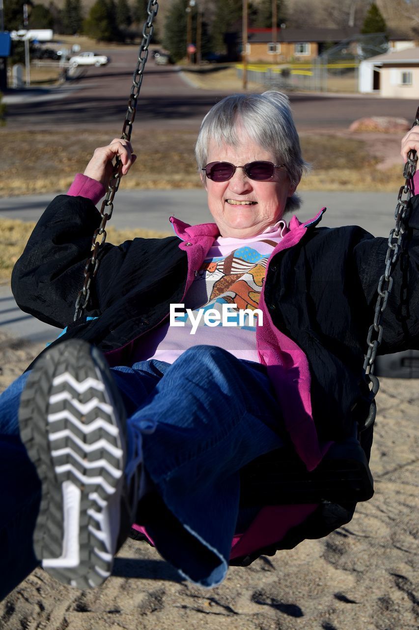 Portrait of woman with sunglasses swinging outdoors