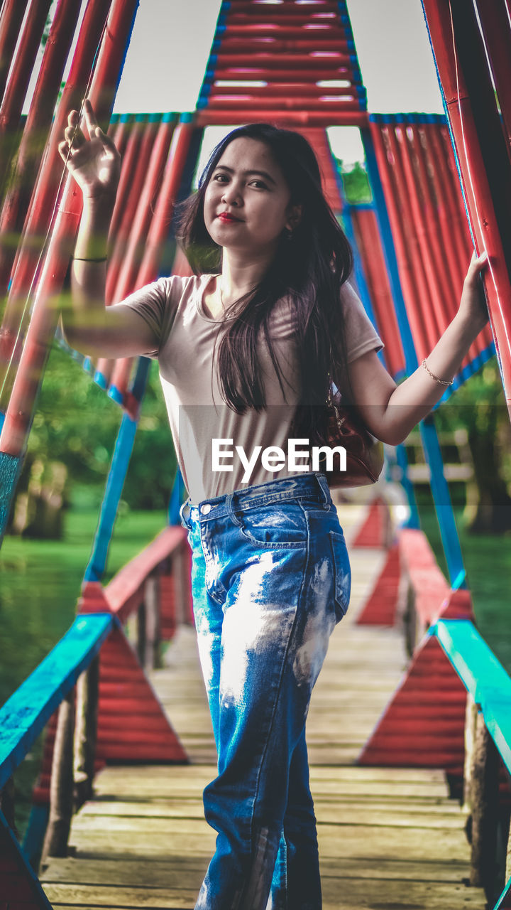 PORTRAIT OF BEAUTIFUL YOUNG WOMAN STANDING AGAINST BUILT STRUCTURE