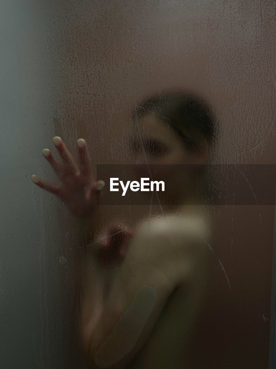 Naked young woman in bathroom seen through window