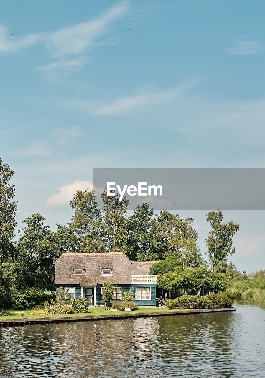 HOUSE BY LAKE AGAINST BUILDINGS