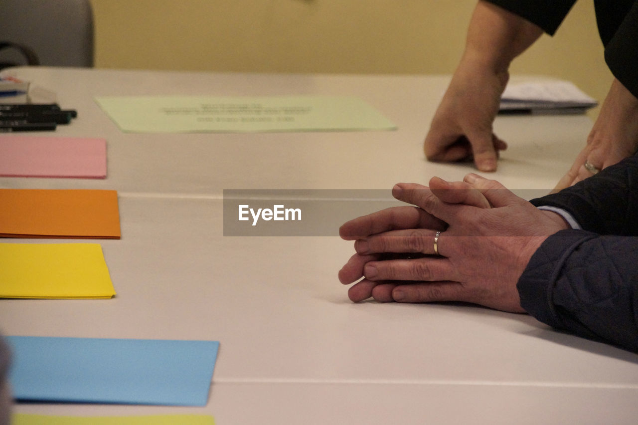 Close-up of people hands on table with colorful papers