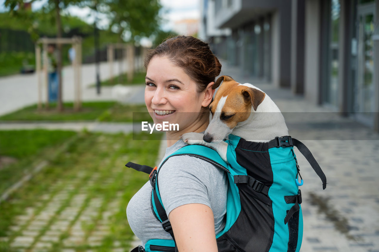 portrait of young woman with dog standing on street