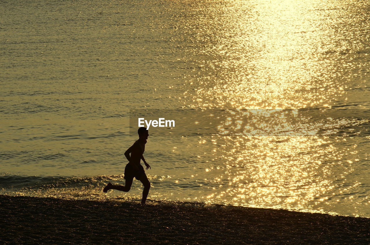 Silhouette man running on beach during sunset