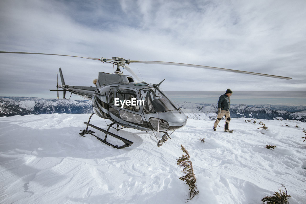 Helicopter pilot explores a snow-covered mountain summit.