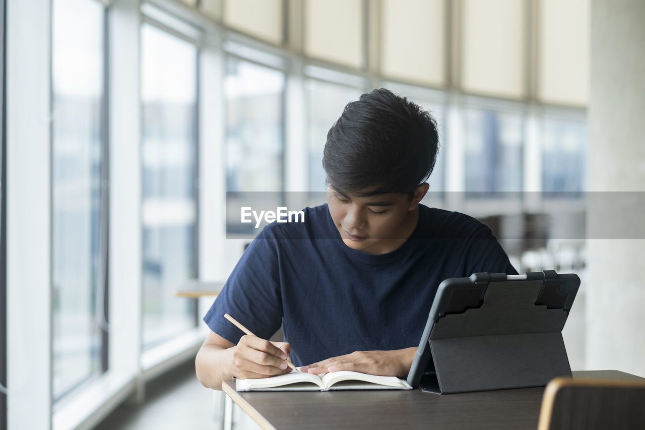 Young collage student using computer and mobile device studying