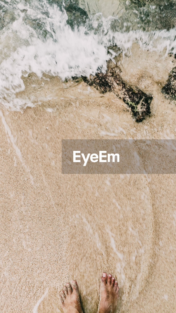 low section of woman sitting on sand at beach