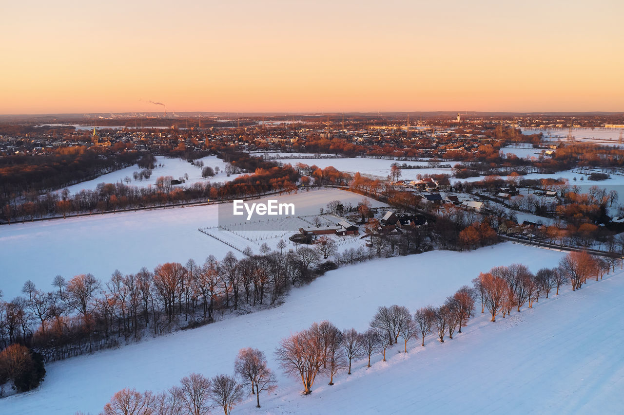 Drone view of landscape and fields in germany covered with snow during sunset