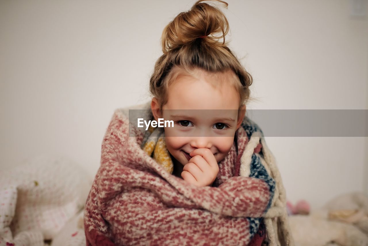 Portrait of a young girl wrapped in a blanket with a smile