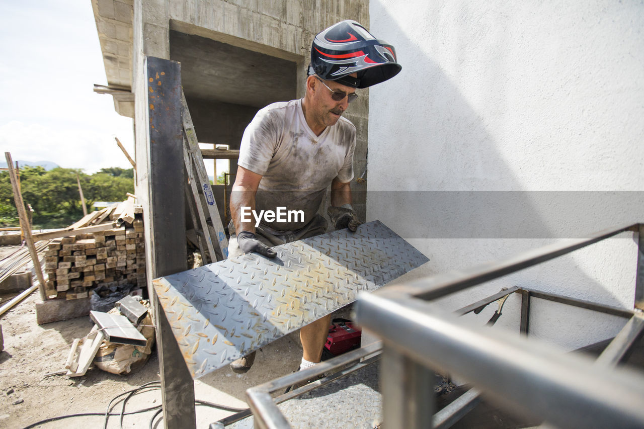 Man works on construction site, building staircase.