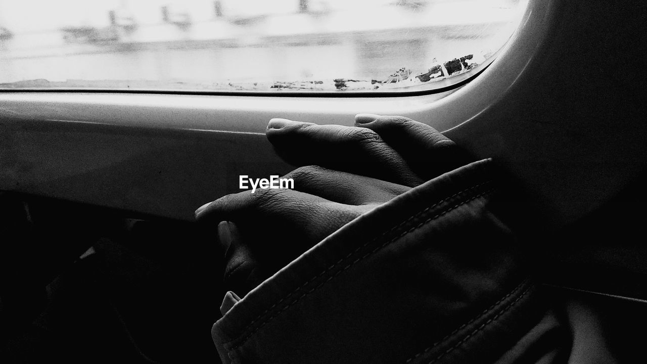 Cropped hand by window in car
