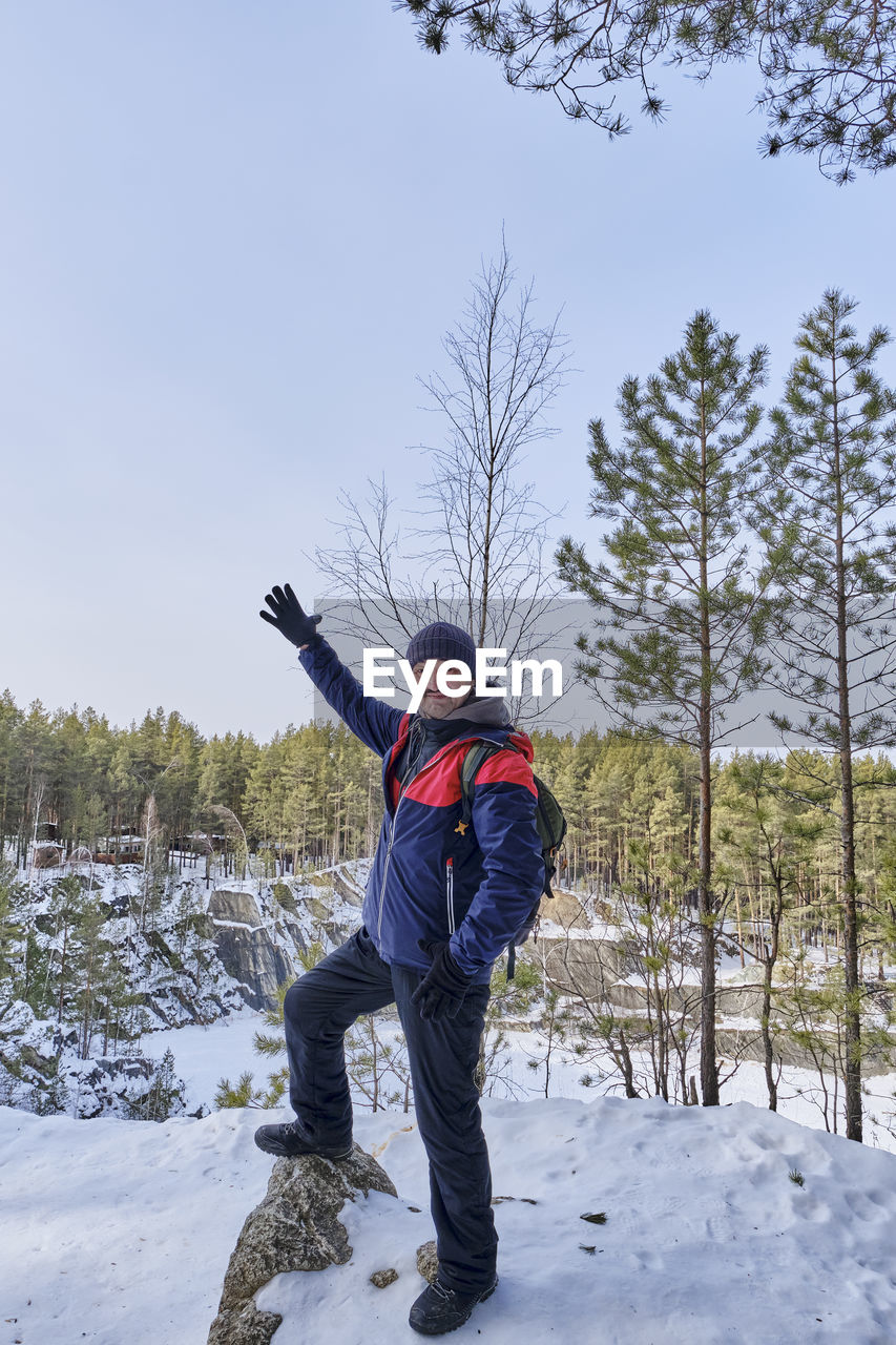 Senior man posing on snowy cliff above scenic frozen talc stone lake in winter, russia