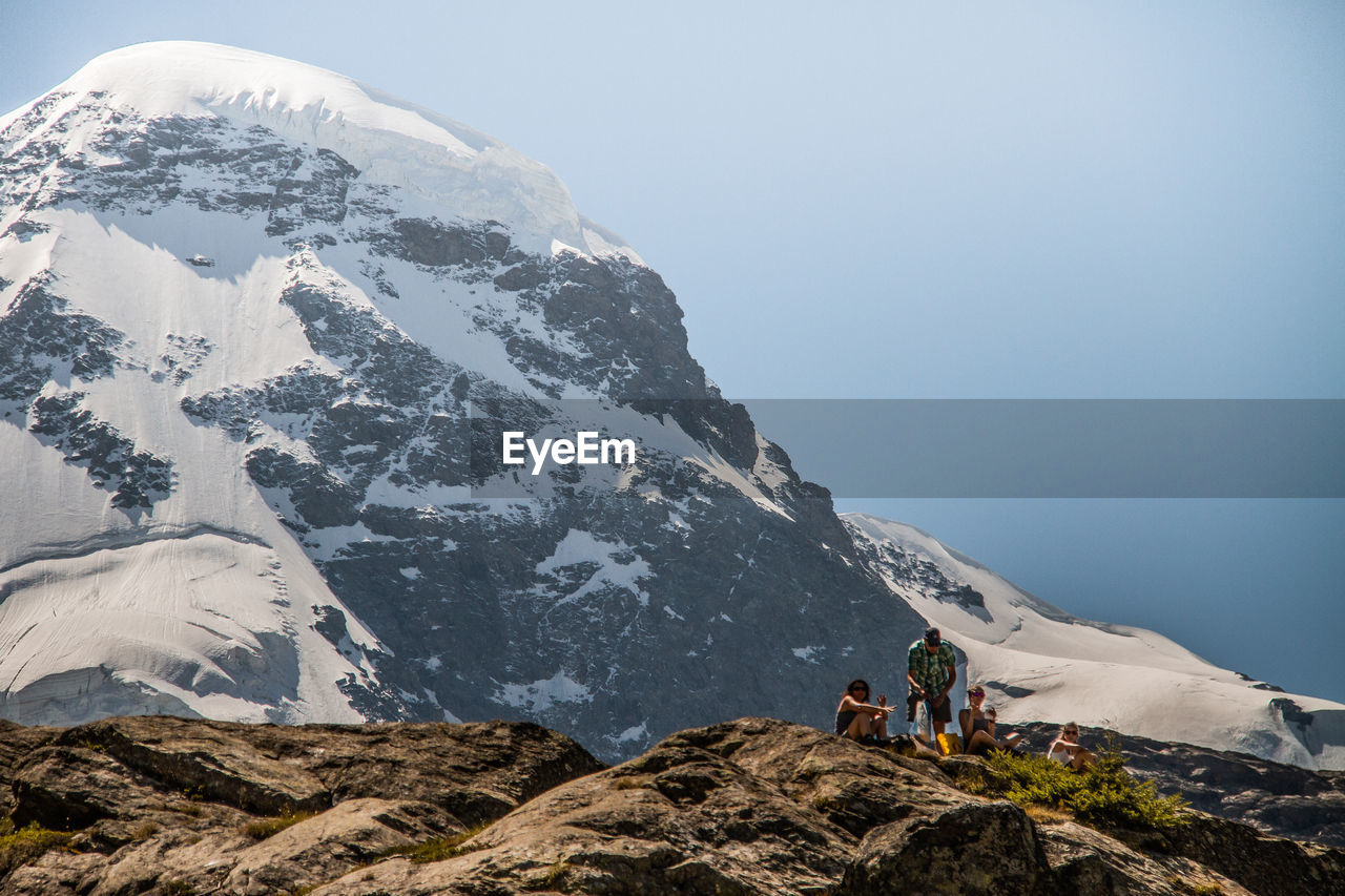 PANORAMIC VIEW OF PEOPLE ON SNOWCAPPED MOUNTAINS AGAINST SKY