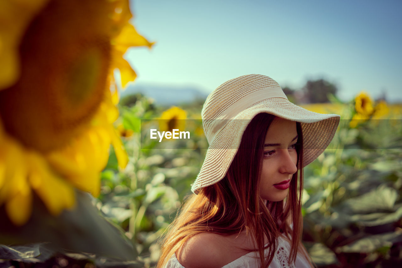 Girl looking away by plants against sky