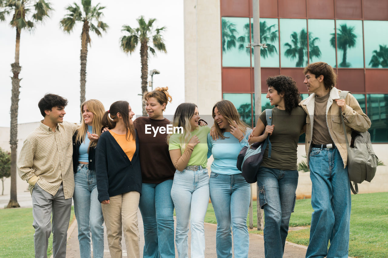 group of friends using digital tablet while standing against wall