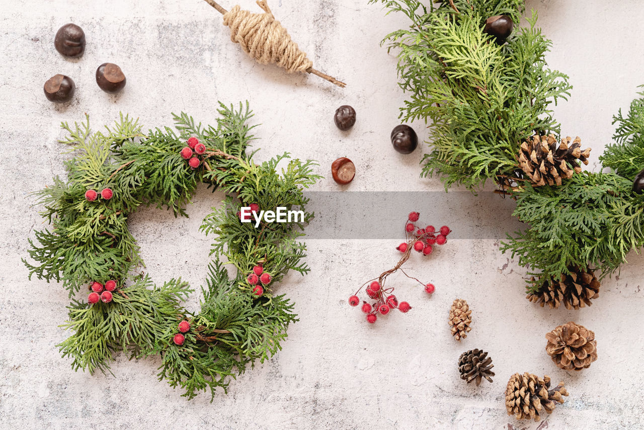 Christmas or new year diy wreath with fir tree branches, vines, pine cones top view on wooden 
