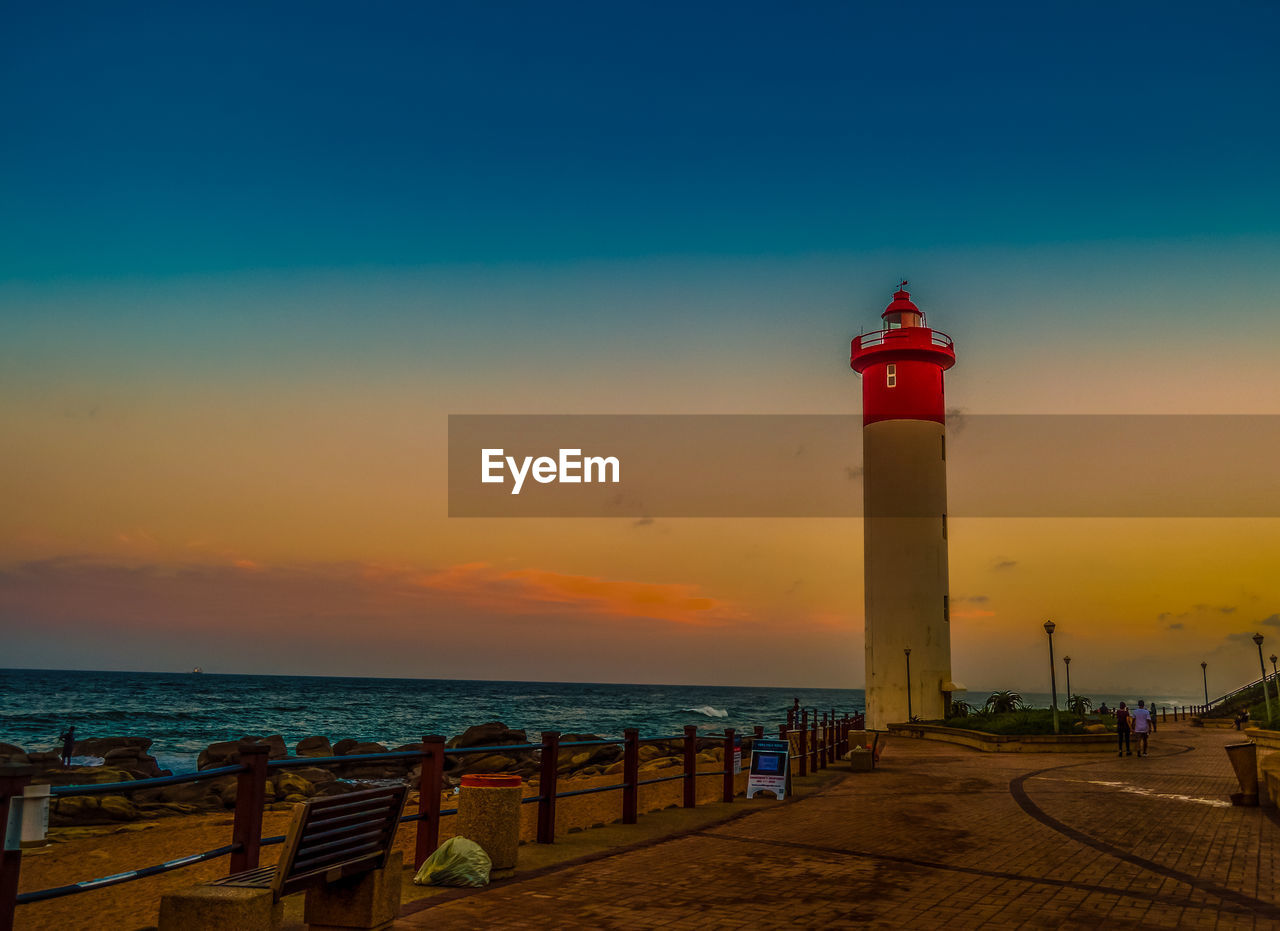 LIGHTHOUSE AMIDST SEA AGAINST SKY DURING SUNSET