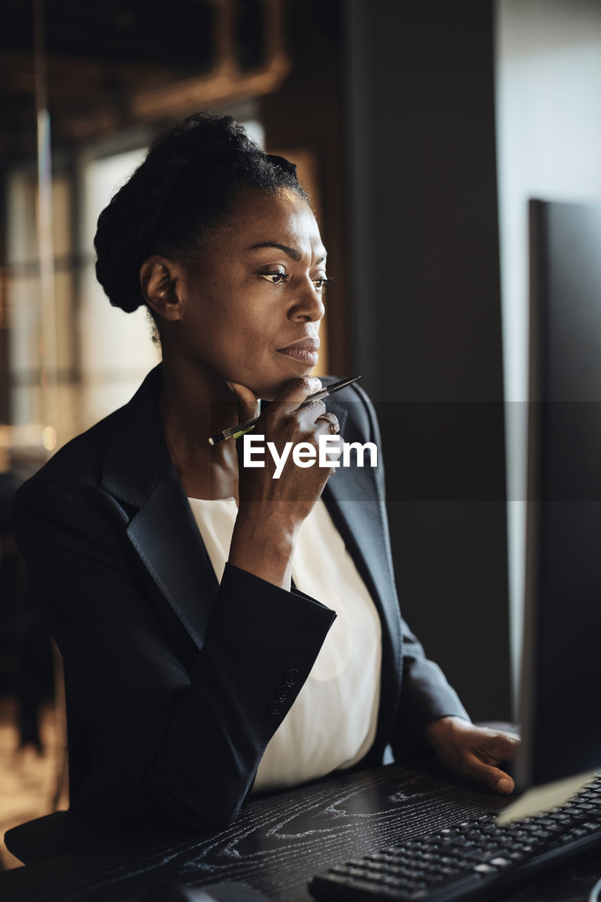 Thoughtful businesswoman with hand on chin working at office