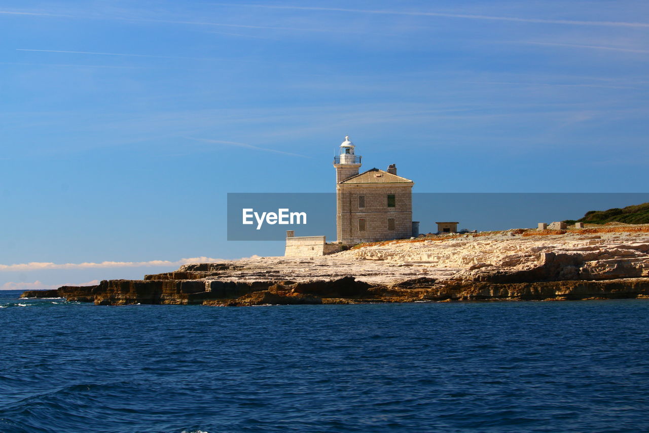 Lighthouse by sea against sky