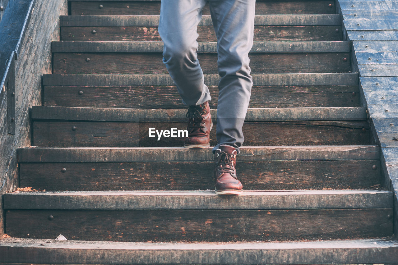 Low section of man walking on steps outdoors