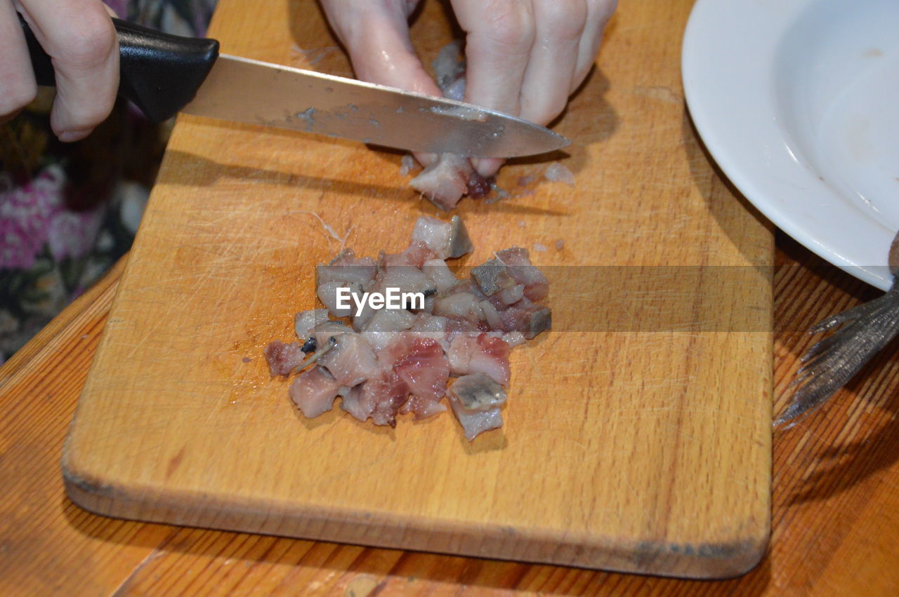 Slicing herring with a knife on a the kitchen board